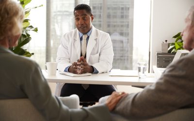 Senior Couple Having Consultation With Male Doctor In Hospital Office